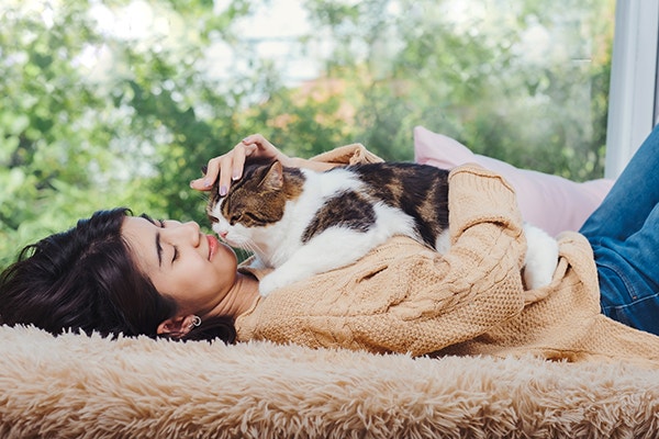 a cat is sitting on a women's chests